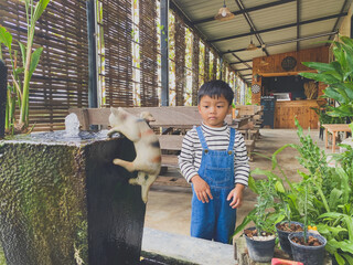 Hispanic child enjoying gardening outdoors with potted plants and watering them in the summer