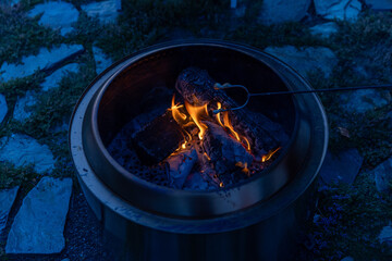Melted Marshmallow on stick in fire pit at night 