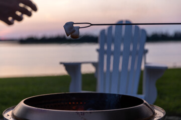 hand reaching for Marshmallows above fire pit 
