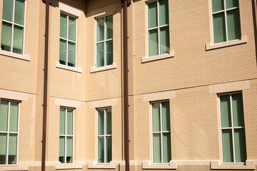 Multi-story building with sun shining directly on wall. Beige stucco exterior wall