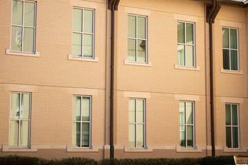 Multi-story building with sun shining directly on wall. Beige stucco exterior wall