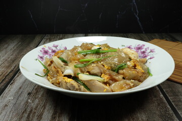 Traditional stirred and fried rice noodle with fresh Chinese kale, peeled shrimp, squid and chicken thigh serving on the plate. Famous special street food menu in Asia.