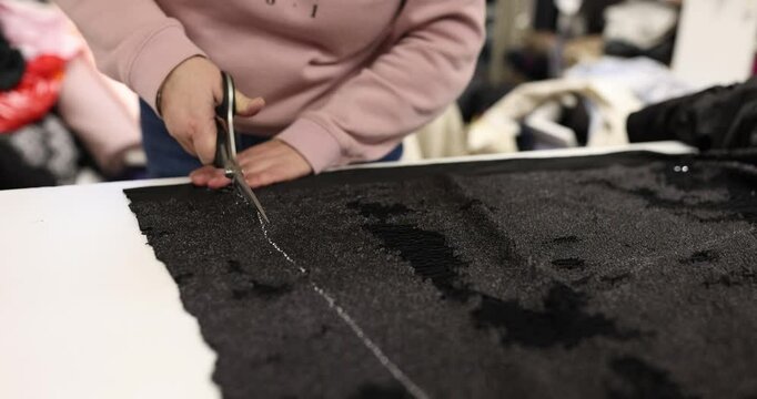 Employee carefully cuts edge of fabric using sharp scissors