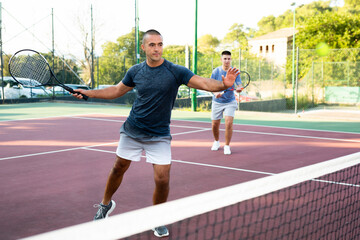 Obraz premium Man in t-shirt playing tennis on court. Racket sport training outdoors.