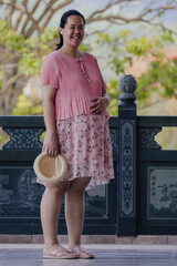 Happy pregnant asian woman at outdoor - pregnancy, people and motherhood concept