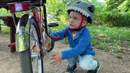 child little boy with wrench playing unscrewing nuts on bicycle in summer park