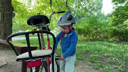 child little boy with wrench playing unscrewing nuts on bicycle in summer park