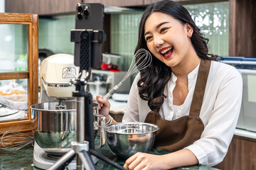 Young asian women is shop owner Put on an apron making cream for cupcakes, Using electric mixer,...