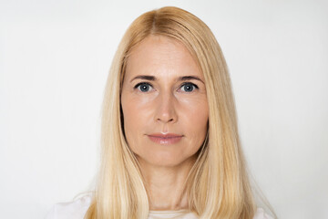 Naklejka premium This image is a portrait of a woman with blonde hair and blue eyes. She is looking directly at the camera and has a neutral expression. She is standing in front of a white background.