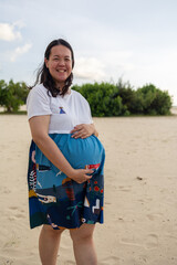 Portrait of happy Asian pregnant woman relax at the beach at sunset