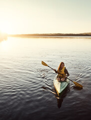 Happy woman, canoeing and ocean with paddle in sunset for travel, hobby or outdoor holiday journey in water, lake or nature. Female person rowing boat with smile on sunshine adventure in kayak at sea © ReeseArcurs/peopleimages.com