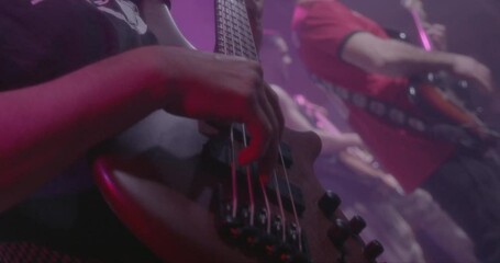 Beautiful slow motion shot of a bassist harshly playing his bass with his fingers during a live performance or concert