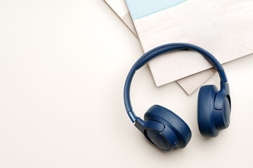 Blue headphones and stack of paper on white background