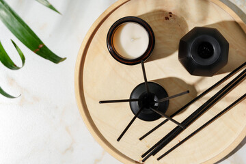 Black Reed Diffuser, Amber Candle, and Wooden Tray on White Surface