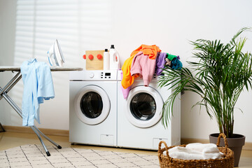 Modern Laundry Room With White Washing Machines, Ironing Board, and Houseplant
