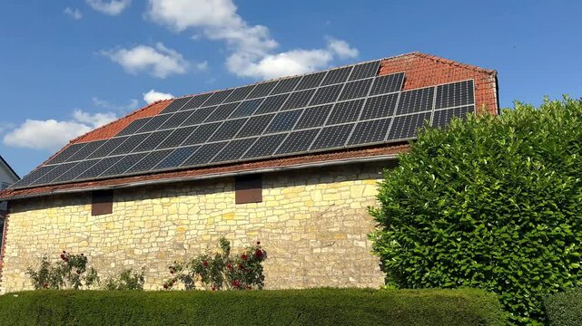 Modern solar panel units on roof of historic sandstone house in German Village. Sunny day with growing rose flower at house wall. Wide shot. Green energy theme. Photovoltaic installation on rooftop.