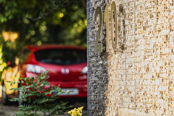 Eine Hausnummer auf einer Strasse in einer großen Stadt mit einem Auto im Hintergrund.