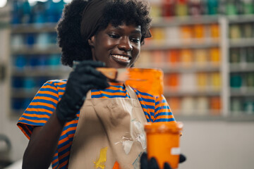 Portrait of diverse graphic worker mixing ink with spatula at facility