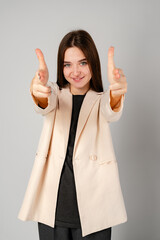 Young Woman Gesturing With Hands In Frame Against Plain Background