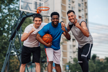 Fototapeta premium Triumphant diverse players with thumbs up on an outside basketaball court