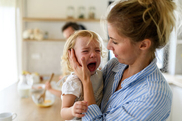 Little girl crying and screaming, mother holding her in arms and soothing her.