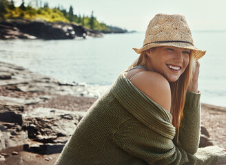 Relax, thinking and happy woman at lake on vacation, holiday and travel outdoor in Switzerland. Water, smile and young person in nature with summer hat for journey, adventure and tourist on trip