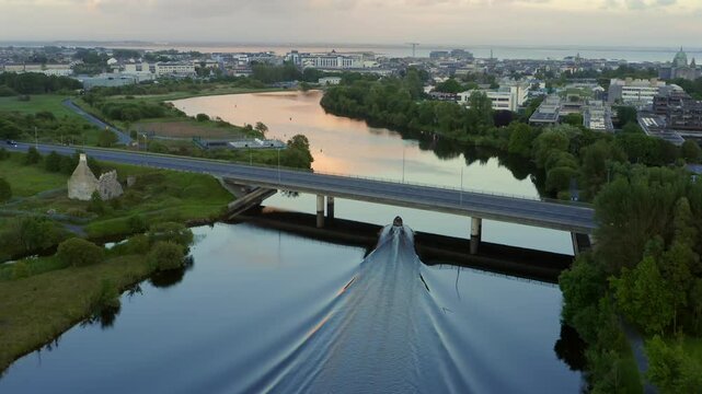 Inflatable boat leaves long wake in water reflecting beautiful sunset in Galway Ireland on the River Corrib