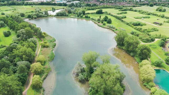 Profile view of Wicksteed park during sunny day with reflection of sky in water in England. Aerial shot. 