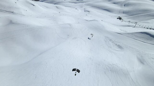 two skydiving parachutes landing on piste in ski resort Tignes, France