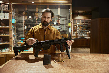 Salesman presenting new model of military gun standing at counter desk