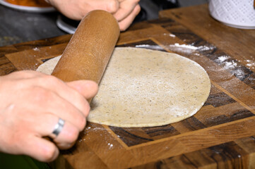 Wałkować surowe ciasto na drewnianej stolicy drewnianym wałkoem