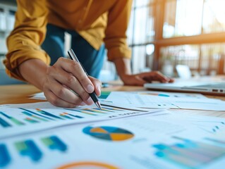 Naklejka premium Close-up of a person analyzing financial data and reports with charts and graphs, highlighting detailed work on business documents.