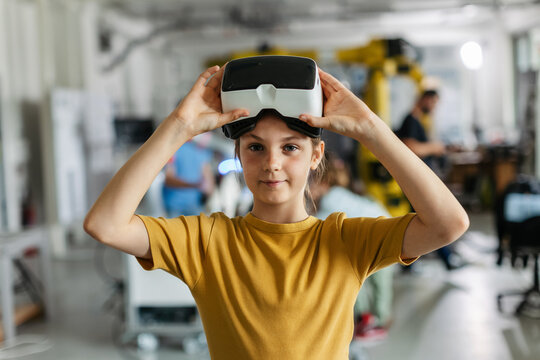 Portrait of schoolgirl with VR headset on head. Children learning robotics in Elementary school, using modern technology, virtual reality.