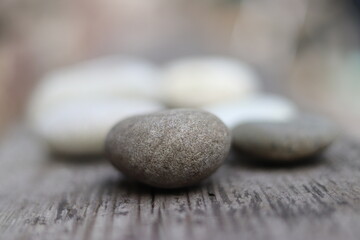Beautiful round stones lie on a wooden floor, close-up, blurred background.