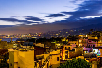Obraz premium beautiful night european town in golden lights with sea shore and nice sunset sky on background