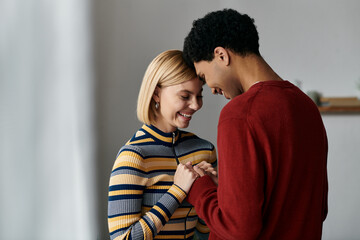 A happy multicultural couple shares a loving moment in their modern apartment, their smiles radiating warmth and connection.