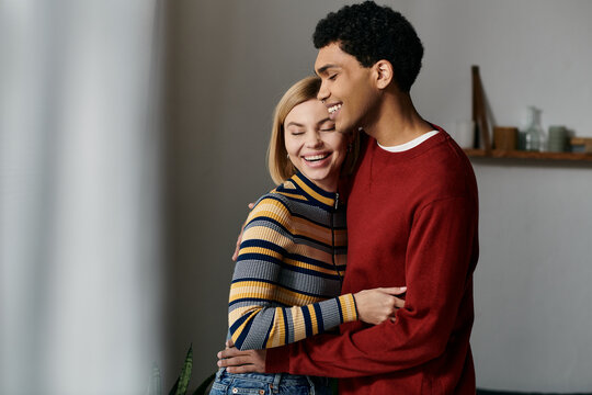 A happy interracial couple embraces and smiles at each other in their modern apartment. - Powered by Adobe