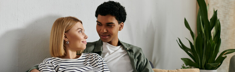 Naklejka premium A young, multicultural couple shares a loving moment in their modern apartment.