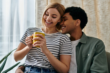 A young, multicultural couple shares a warm moment in their modern apartment, enjoying a cup of coffee together.