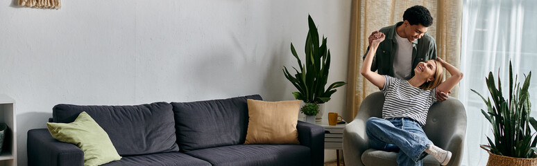 A young multicultural couple enjoys a lighthearted moment in their modern apartment, filled with natural light and greenery.