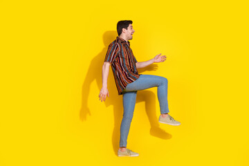 Full size profile photo of nice young man walk empty space wear shirt isolated on yellow color background