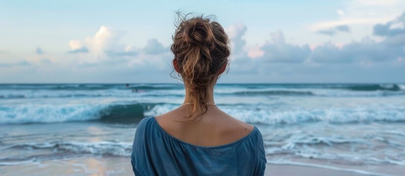 Unidentified female facing away from the camera, appreciating the beach horizon. Empty space for text.