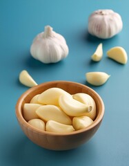 Fresh peeled garlic in bowl on blue background