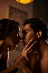 A young Asian woman in black lingerie and an African American man share a passionate moment in bed.