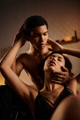 A young Asian woman in black lingerie seduces an African American man on a bed.