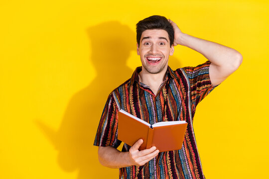 Portrait of nice young man hold book empty space wear shirt isolated on yellow color background
