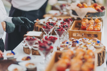 hands of a waiter prepare food for a buffet table in a restaurant. caterer arranges array of...