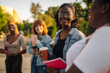 Diverse college girl walking at campus and smiling at classmate.