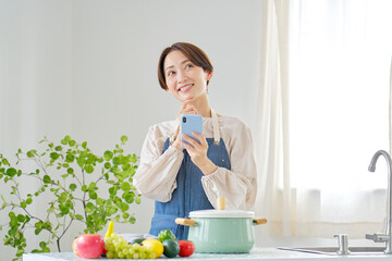 キッチンで想像しながらスマホを使う女性