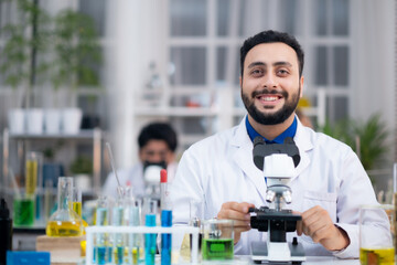 Portrait of confident medical researcher in laboratory with microscope smilling.